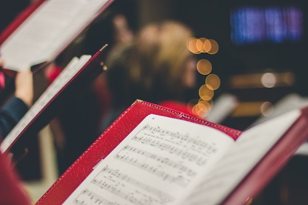 Person holding sheet music with lighted tree in background